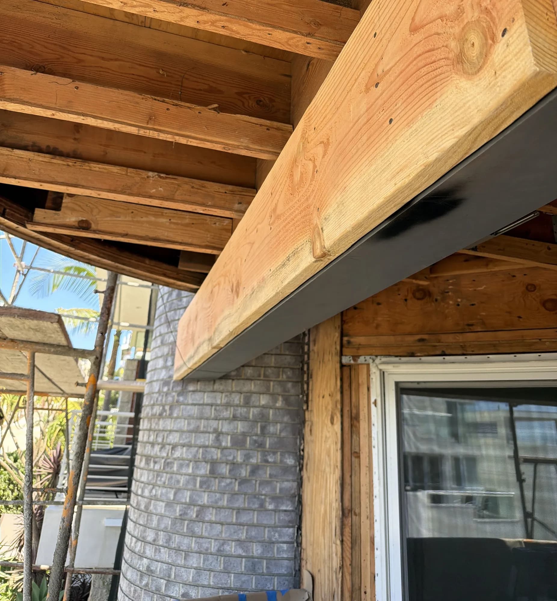 New steel beam with a wood nailer carrying the roof framing over an open patio