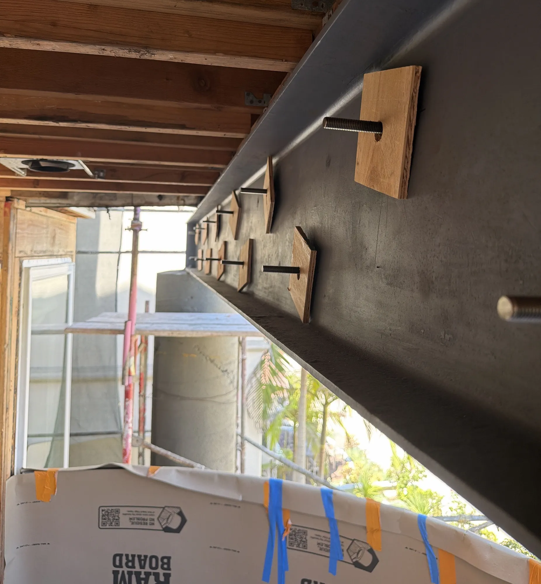 Steel I-beam with welded studs and wood nailer blocks under existing floor framing
