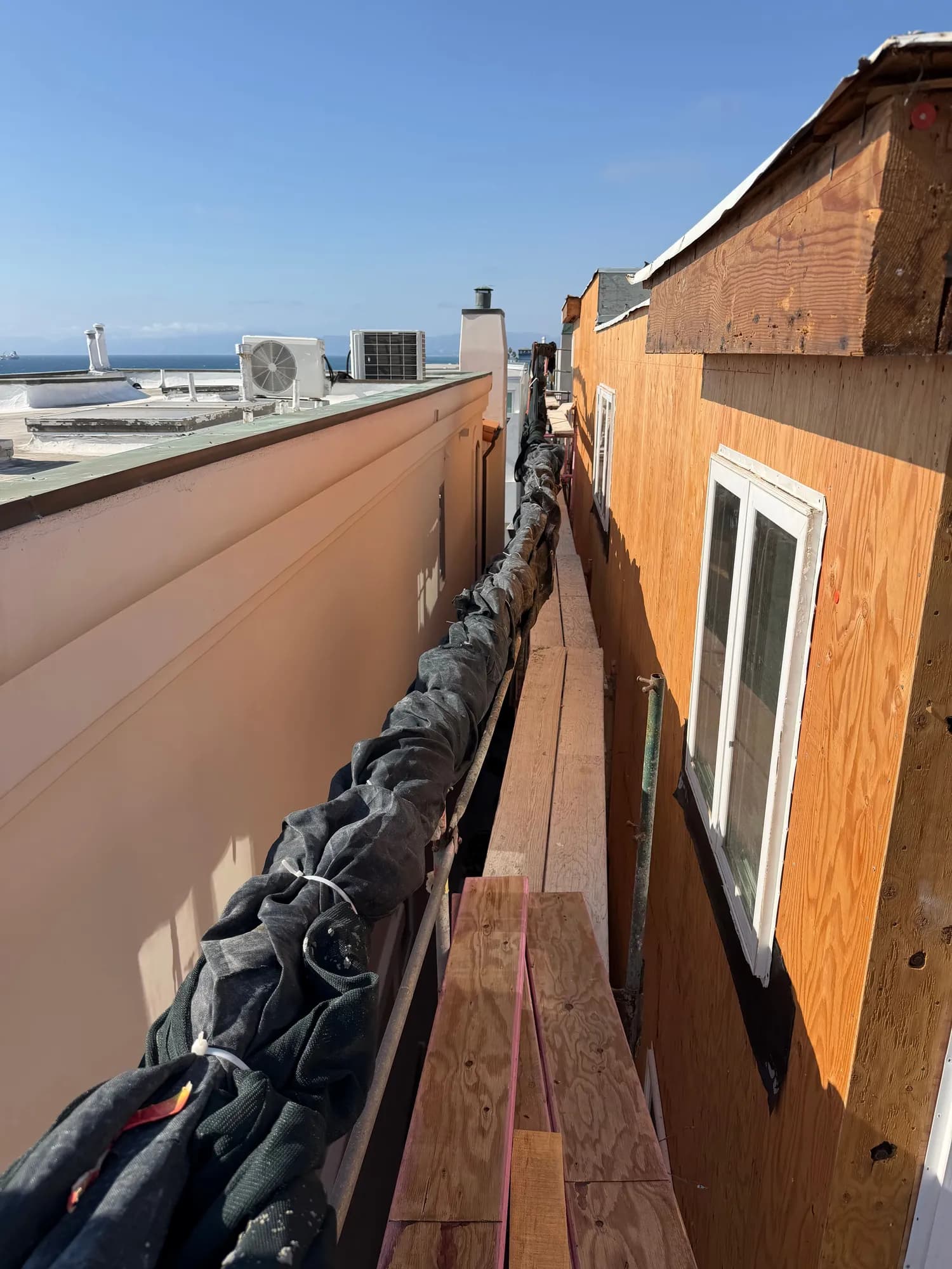 Narrow side yard with new windows set in plywood sheathing on a Manhattan Beach home