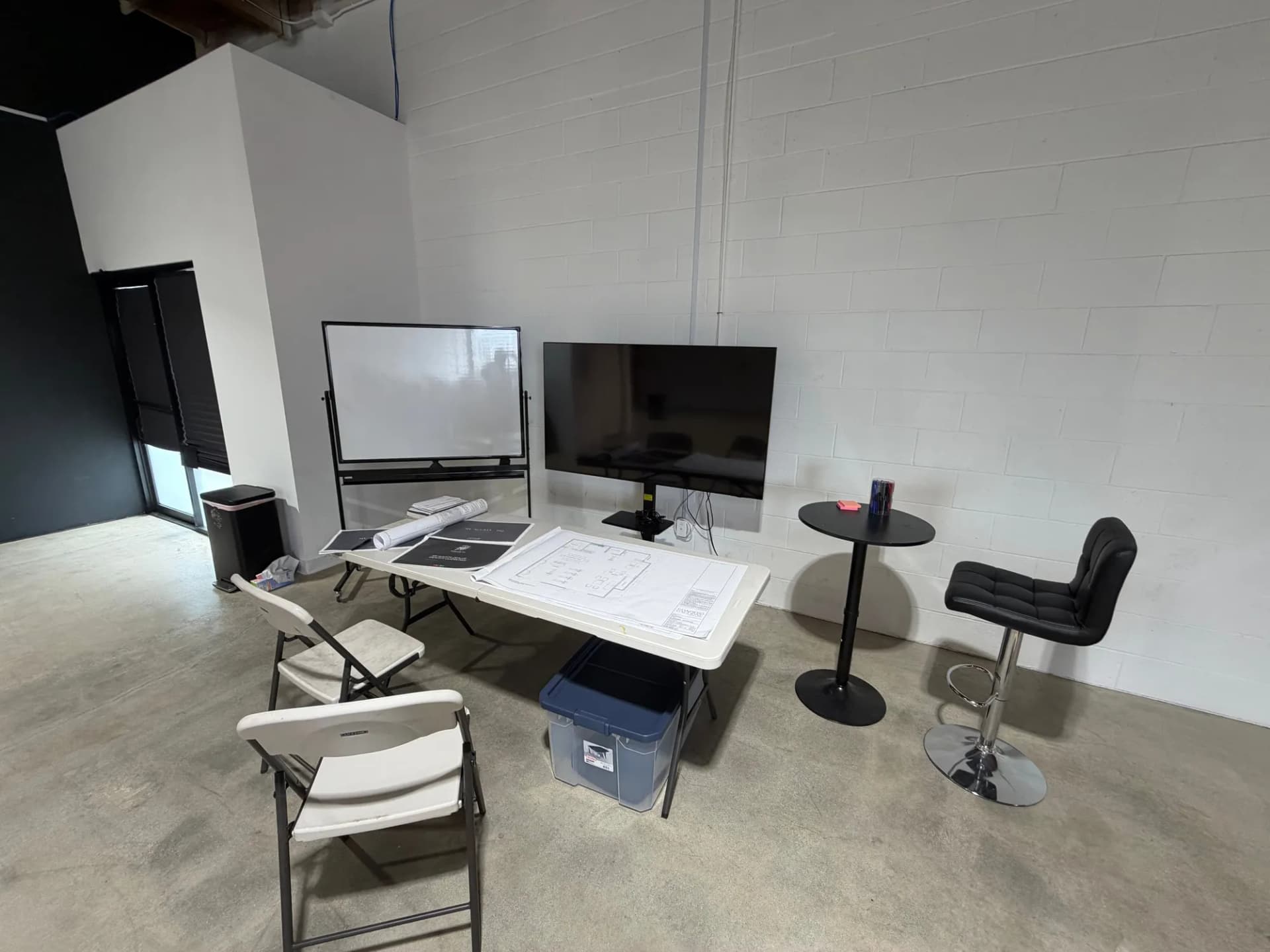 Site-office corner with plans laid out on a table and a whiteboard
