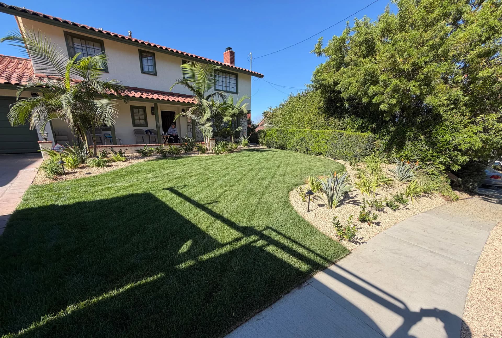 New lawn sweeping past drought-tolerant planting toward a Spanish-style home