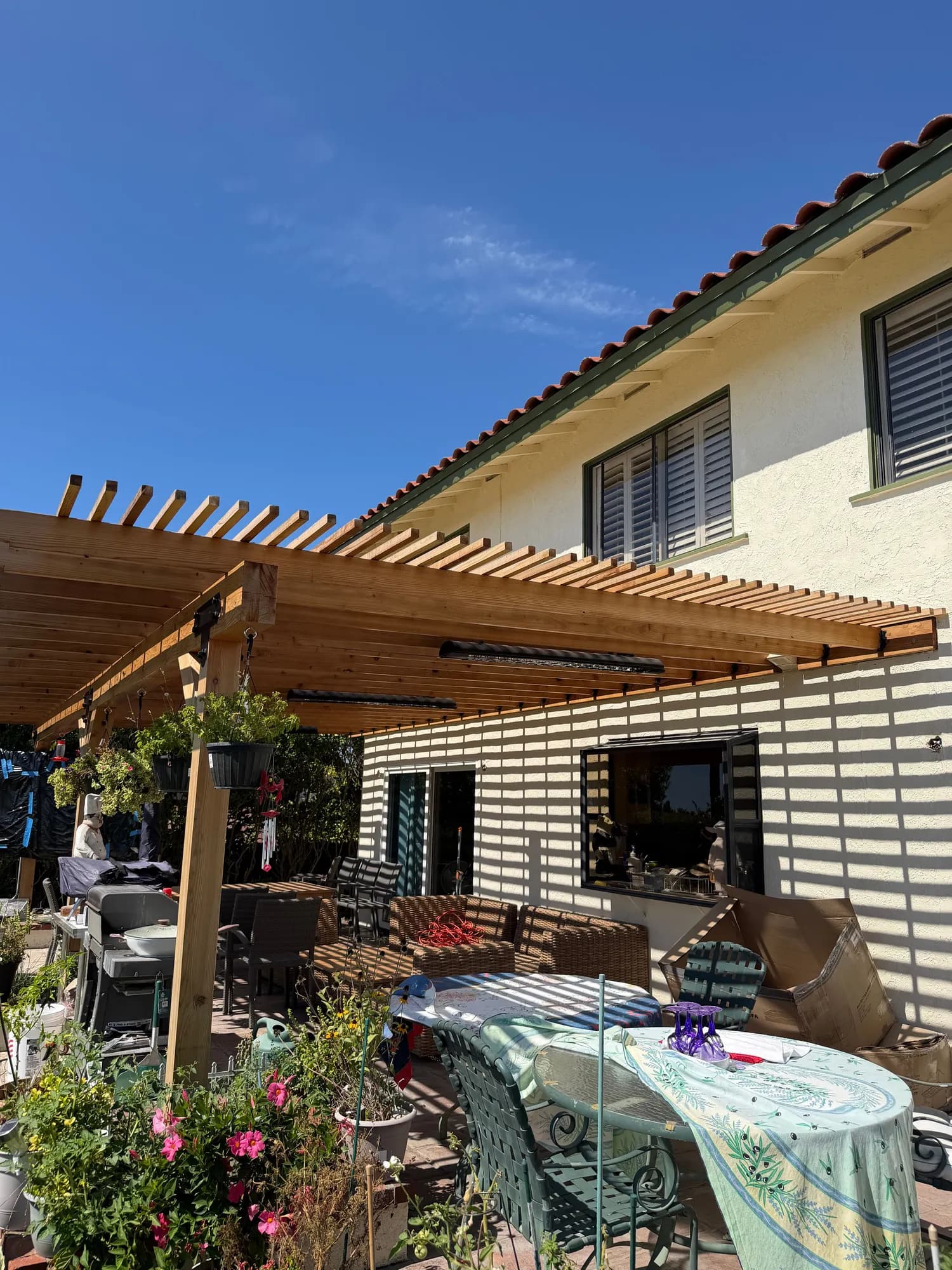 Redwood pergola with infrared heaters over an outdoor dining patio