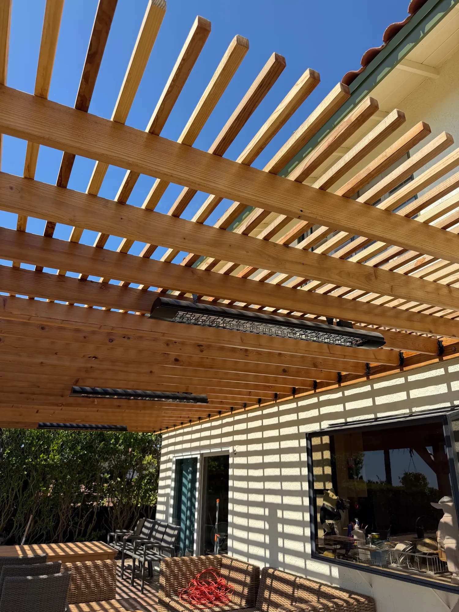 Redwood pergola rafters with a mounted infrared heater above a lounge area