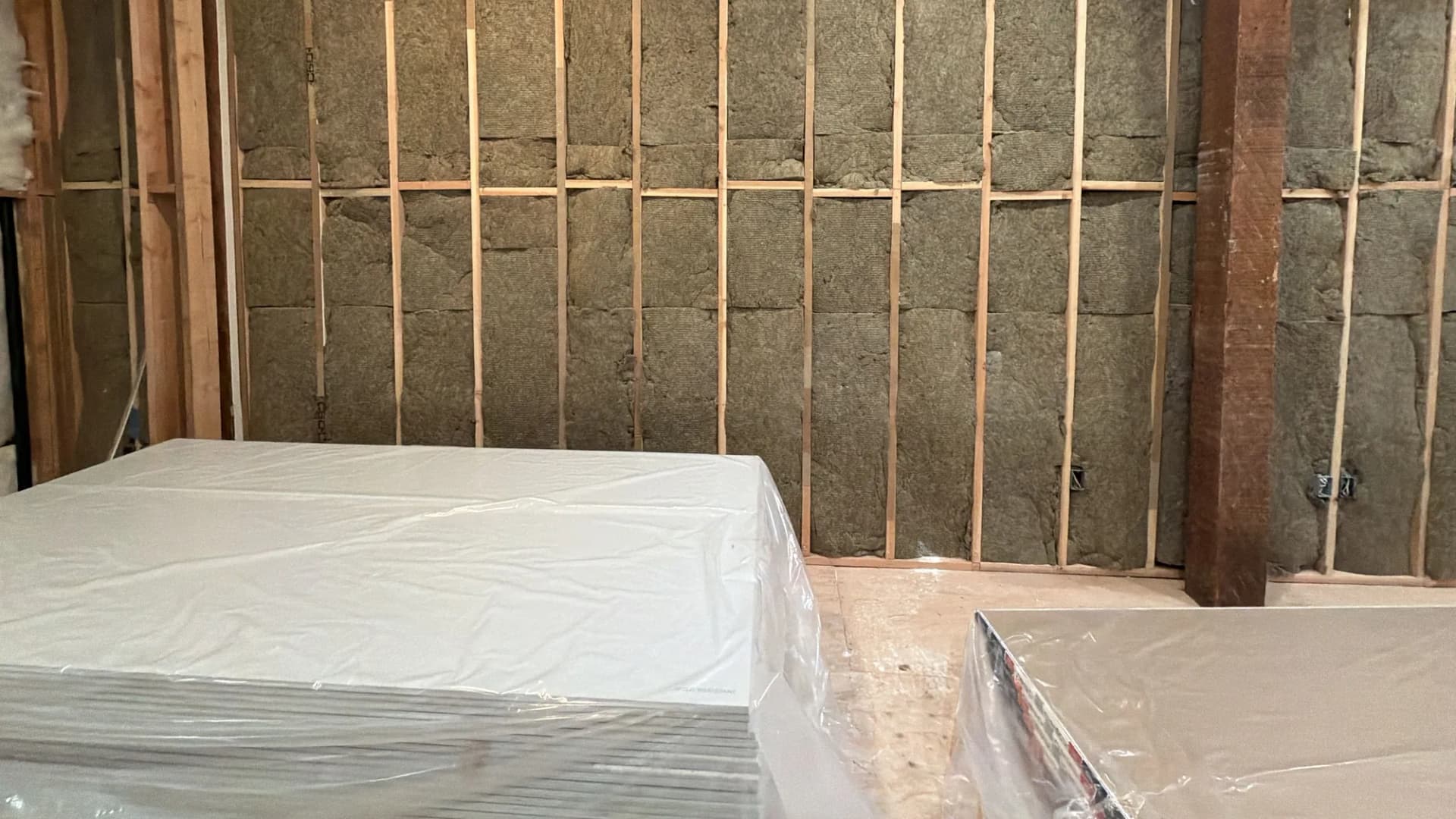 Insulated stud wall with drywall staged for hanging