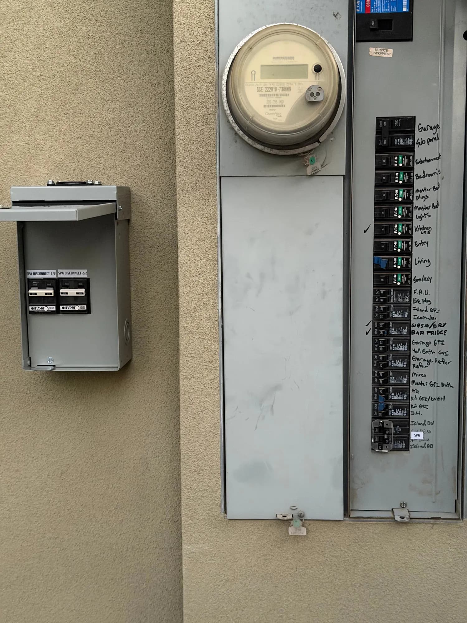Main electrical panel beside a new outdoor spa disconnect subpanel on a stucco wall